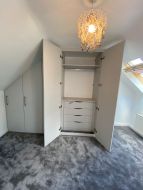 Hinged wardrobes fitted into the gable end of a loft conversion with fitted drawers (straight on view)