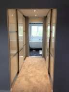 Wardrobes on both sides of a corridor between the bedroom and ensuite (door open)